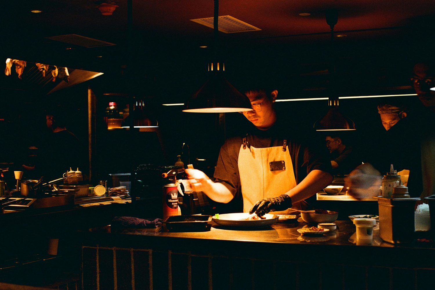 La ligne de cuisine pendant le service, en lumière tamisée